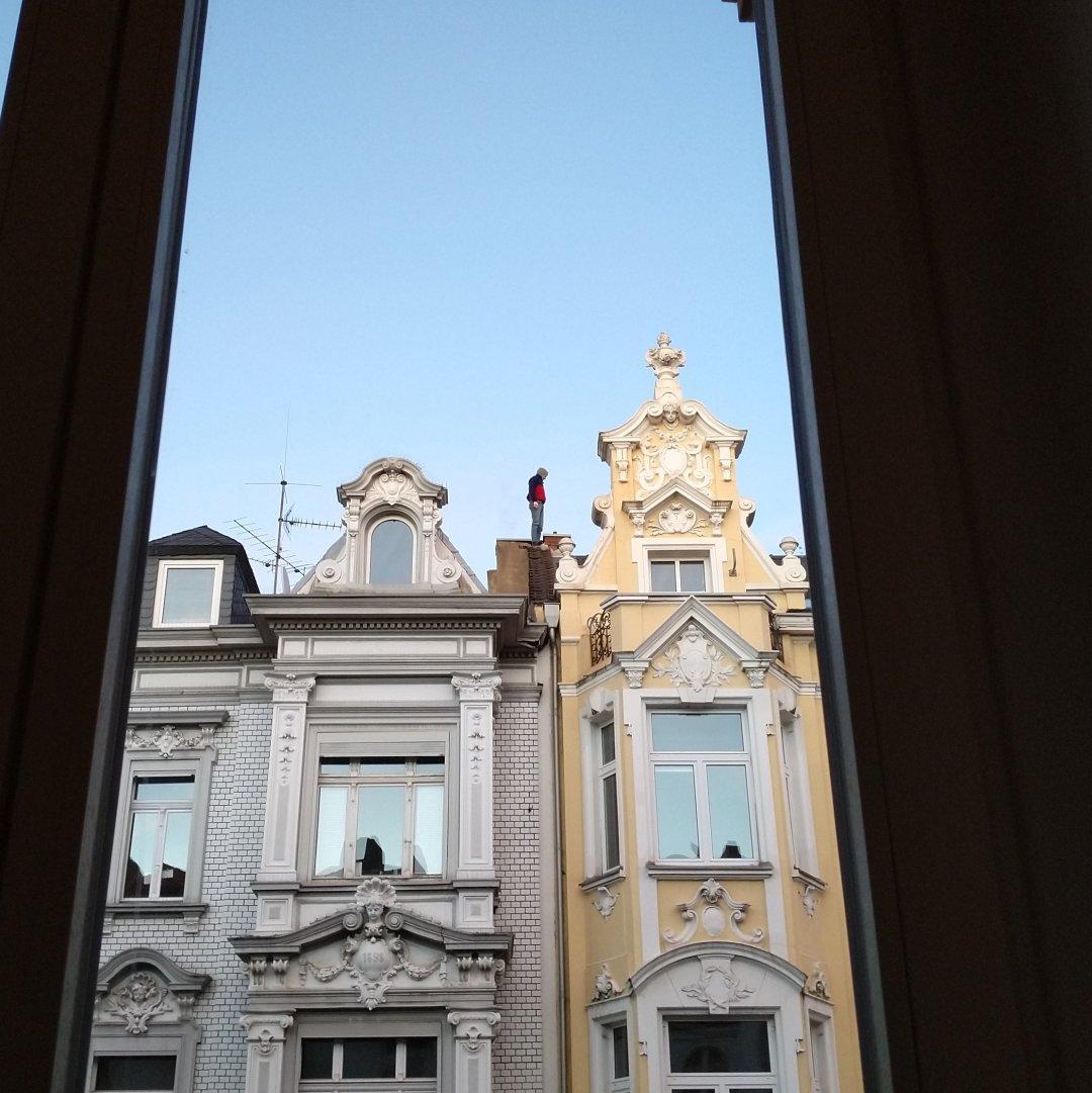 A man standing on a rooftop in the evening sun.