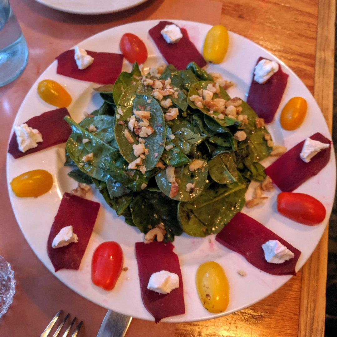 A beautiful salad with cherry tomatoes, beet slices and cheese arranged around the edges in an artistic fashion